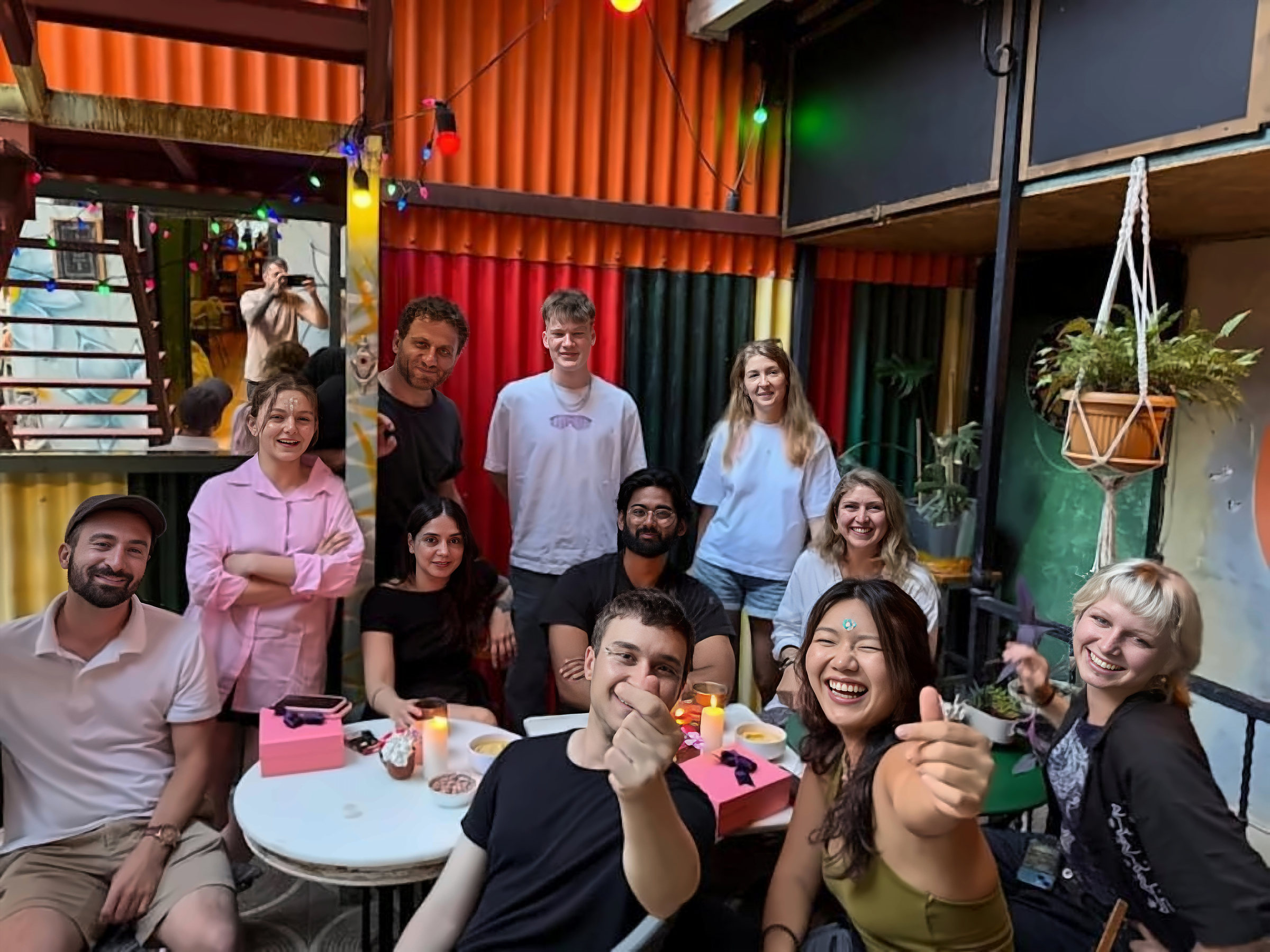 Smiling guests gathered around a table in the colourful courtyard at YOLO Hostel