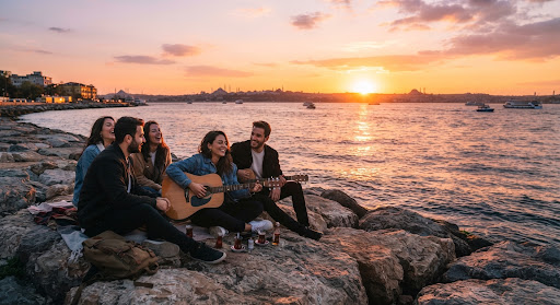 People on the seaside rocks in Moda watching the sunset with a guitar